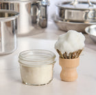 Jar of goat milk dish soap with wooden brush in a kitchen