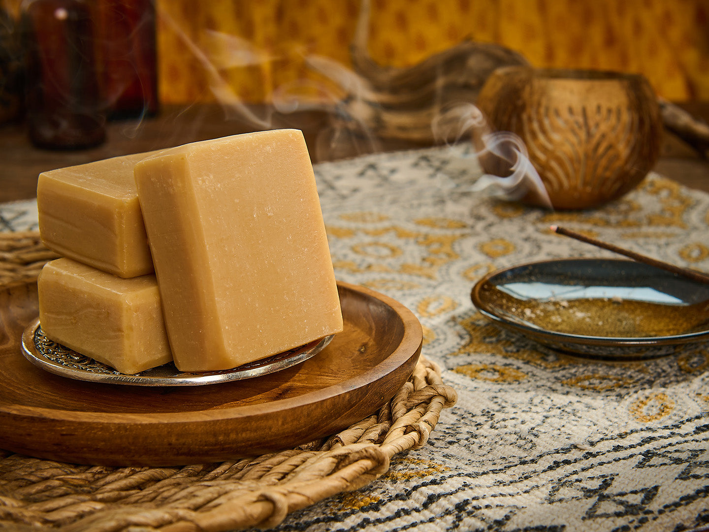 Three bars of soap on a wooden tray with a textured background