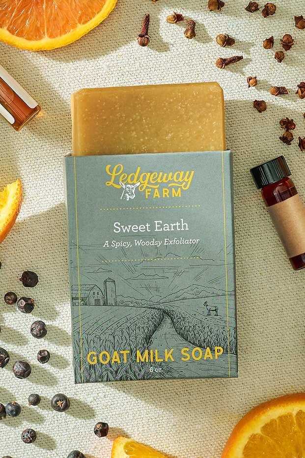 Goat milk soap bar from Ledgeway Farm with packaging on a textured surface with oranges and spices.