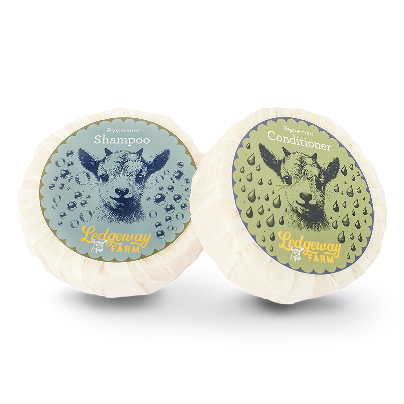 Two goat milk shampoo and conditioner bars with labels on a white background