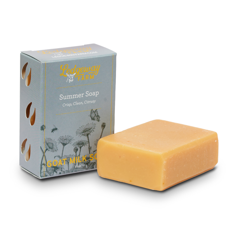 Bar of summer goat milk soap and its packaging on a white background