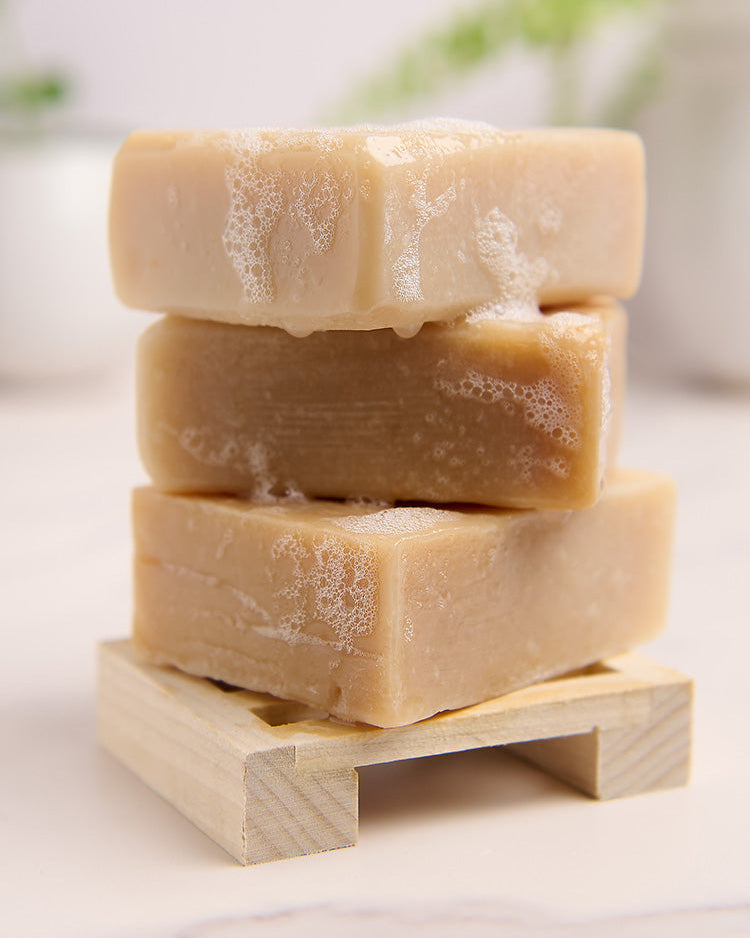 Stack of three bars of soap on a wooden stand with a blurred background