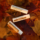 Three Ledgeway Farm lip balm products on a bed of autumn leaves