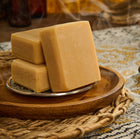 Three bars of soap on a wooden tray with a textured surface in the background