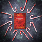 Peppermint goat milk soap on a dark background surrounded by candy canes
